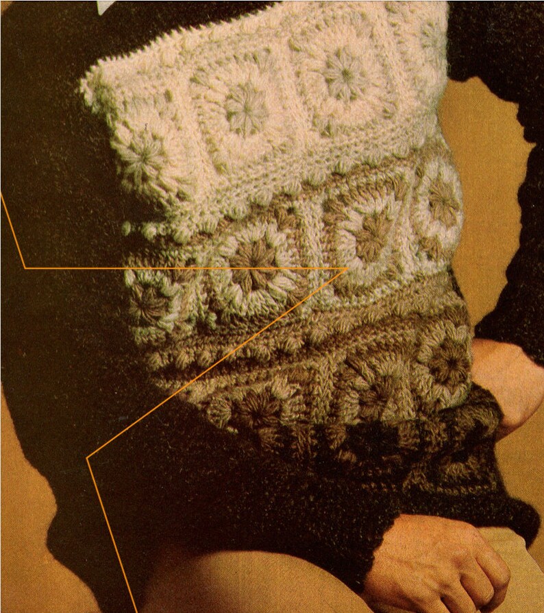 Puede incluir: Un su&eacute;ter marr&oacute;n con un dise&ntilde;o de crochet blanco. El su&eacute;ter tiene un patr&oacute;n texturizado con un motivo floral.