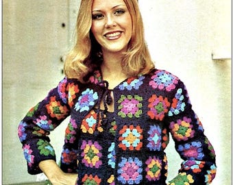 May include: A long-sleeved crochet cardigan and matching top set constructed from dark navy blue granny squares. Each square features a vibrant, multi-colored floral center in shades of pink, green, orange, and light blue. The cardigan has a tie closure.