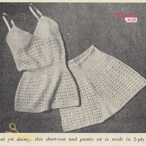 Puede incluir: Un conjunto de top corto y bragas de ganchillo blanco. El conjunto está hecho con un delicado patrón de punto abierto.