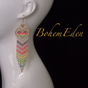 May include: Rainbow heart-shaped beaded earrings with a gold accent. The earrings are long and dangle, with a chevron pattern.