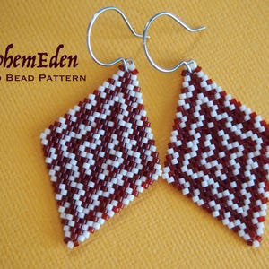Op de afbeelding: Een paar witte en kastanjebruine diamantvormige oorbellen met zilveren haakjes. De oorbellen zijn gemaakt van kralen en hebben een geometrisch patroon.