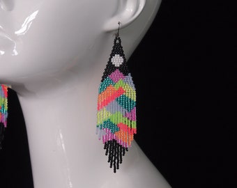 full moon over an abstract neon mountain range: colorful long beaded fringes with black contrast. bold and colorful statement earrings.