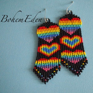 May include: A pair of rainbow heart beaded earrings with black beads and silver hooks. The earrings are long and dangle.