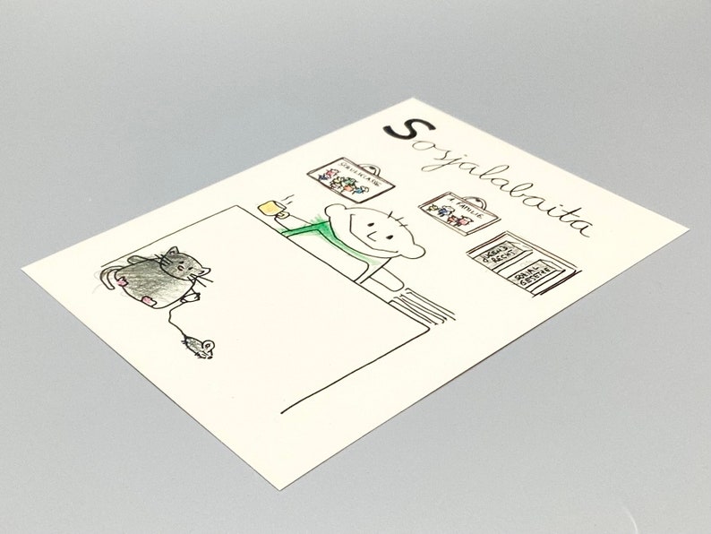 Peut inclure: Une carte rectangulaire blanche avec un dessin au trait &agrave; l'encre noire repr&eacute;sentant une personne tenant une tasse jaune, un chat gris jouant avec une souris jouet et des cadres muraux. Le texte Sosjalabaita est imprim&eacute; en noir en haut &agrave; droite.