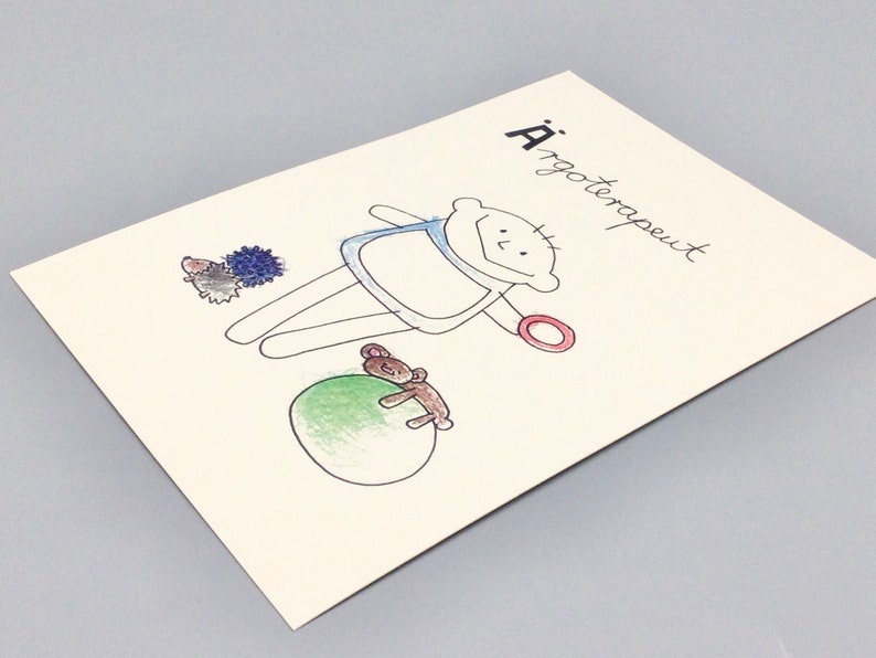 May include: A hand-drawn illustration of a person with a red ring, a blue shirt, and a green ball. The person is holding a teddy bear. The illustration is on a white card with the text "A'rgoterapeut" written in black.