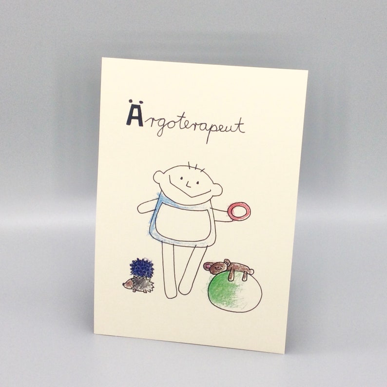 May include: A card with a hand-drawn illustration of a child holding a red ring. The text "&Auml;rgoterapuet" is written in black at the top of the card.