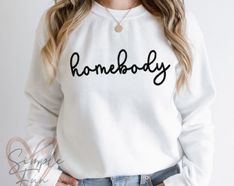 May include: White sweatshirt with the text "homebody" written in black cursive script.