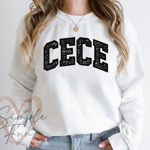 May include: White sweatshirt with black glitter lettering that says "CECE".