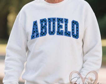 May include: White sweatshirt with a blue and black plaid design that says "ABUELO" in blue outlined letters.