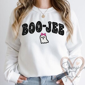 May include: White sweatshirt with the text "BOO-JEE" in black, outlined in white, above a cartoon ghost with a pink bow. The sweatshirt is a crew neck style.