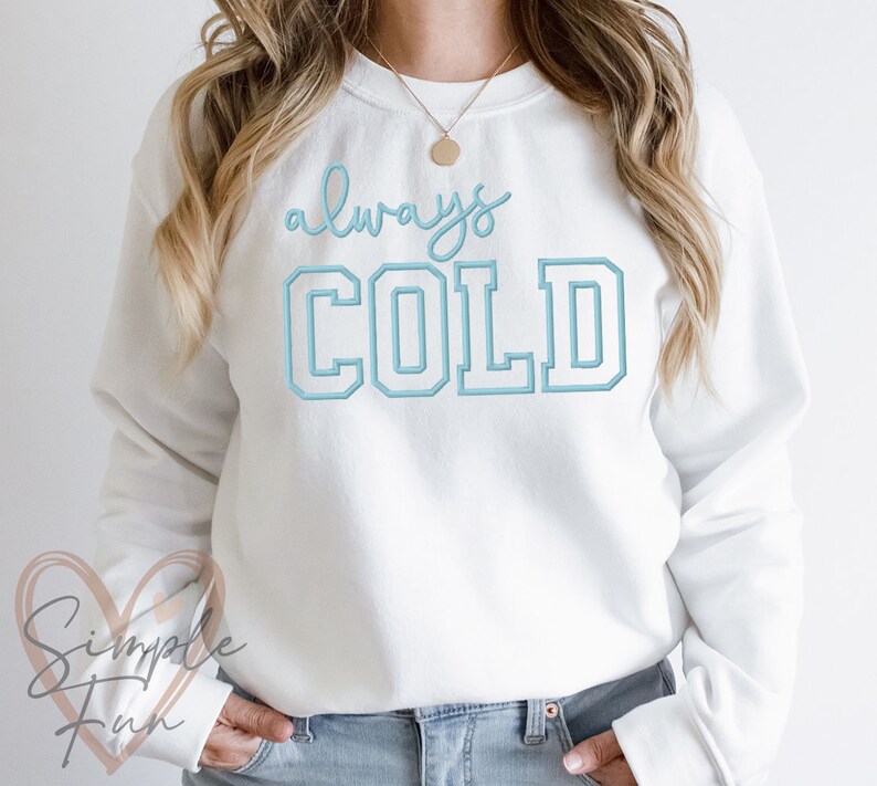 May include: White sweatshirt with the text "always COLD" in blue lettering. The text is in a varsity style font.