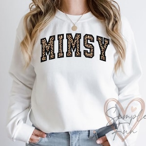 Op de afbeelding: Wit sweatshirt met het woord "MIMSY" in grote letters op de borst. De letters hebben een luipaardprint met een zwarte omlijning. Het sweatshirt heeft een ronde hals.