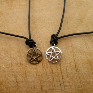 May include: Two leather necklaces with pentagram pendants. One pendant is silver and the other is bronze.