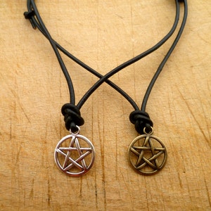 May include: Two leather necklaces with pentagram pendants. One pendant is silver and the other is gold.