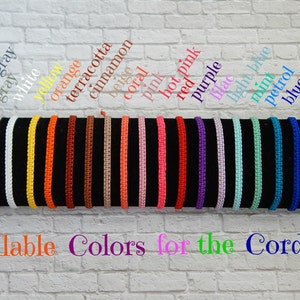 May include: A display of 18 different coloured cords, showing the available colours for a cord bracelet. The colours are black, dark grey, grey, white, yellow, orange, terracotta, cinnamon, beige, coral, pink, hot pink, red, purple, light blue, mint, petrol, blue, green, and light green. The text "Available Colors for the Cord" is displayed below the cords.