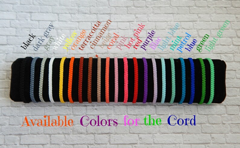 May include: A display of 18 different coloured cords, showing the available colours for a cord bracelet. The colours are black, dark grey, grey, white, yellow, orange, terracotta, cinnamon, beige, coral, pink, hot pink, red, purple, light blue, mint, petrol, blue, green, and light green. The text "Available Colors for the Cord" is displayed below the cords.