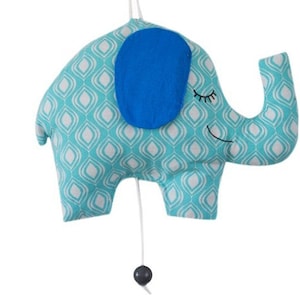 May include: A blue and white patterned elephant wind-up musical toy with a blue felt ear and a black and white face. The toy has a pull string and a black ball at the end of the string.