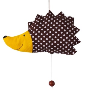 Könnte beinhalten: Ein braunes und weißes gepunktetes Igel-Hängemobil mit gelbem Gesicht und einer Holzkugel am Boden.