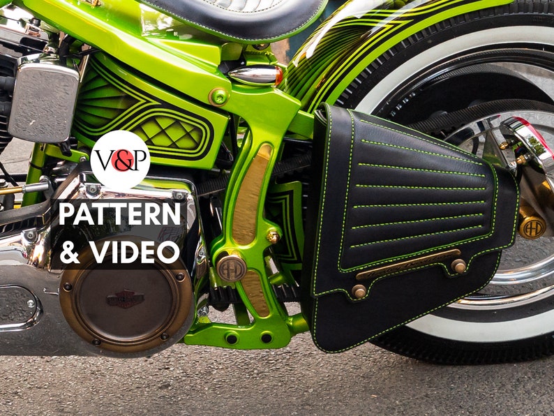 May include: A green motorcycle with a black leather saddlebag with yellow stitching. The motorcycle has a gold-colored frame and a black and white tire. The saddlebag has a brass buckle and a brass plate with the text "V&P PATTERN & VIDEO".