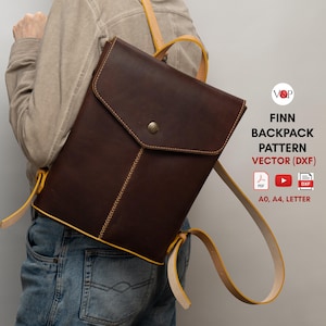 Peut inclure: Un sac à dos en cuir marron avec des coutures et des sangles jaunes. Le sac à dos a un rabat avec une fermeture à bouton. Le texte "FINN BACKPACK PATTERN VECTOR (DXF) PDF ► DXF A0, A4, LETTER" est visible sur l'image.