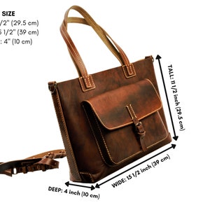 Puede incluir: Un bolso tote de cuero marr&oacute;n con un bolsillo frontal y cierre de hebilla. El bolso mide 29,5 cm de alto, 39 cm de ancho y 10 cm de profundidad. Tiene una correa para el hombro y asas superiores. Las costuras son visibles.