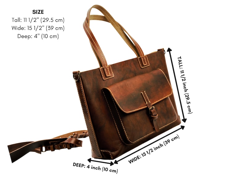 Puede incluir: Un bolso tote de cuero marr&oacute;n con un bolsillo frontal y cierre de hebilla. El bolso mide 29,5 cm de alto, 39 cm de ancho y 10 cm de profundidad. Tiene una correa para el hombro y asas superiores. Las costuras son visibles.