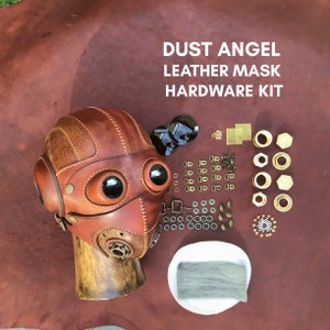 Może przedstawiać: Brązowa skórzana maska z okularami i zestawem okuć. Zestaw zawiera nity, zatrzaski, oczka i inne okucia. DUST ANGEL LEATHER MASK HARDWARE KIT jest napisane białym kolorem na brązowym tle.