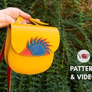 May include: A yellow leather crossbody bag with a red, blue, and yellow hedgehog design. The bag has a red strap and is made of leather. The text "PATTERN & VIDEO" is visible in the image.