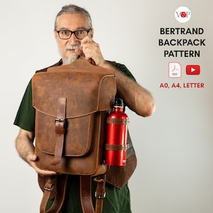 Può includere: Uno zaino in pelle marrone con un porta bottiglia. Lo zaino ha una grande patta con chiusura a fibbia. Il testo "BERTRAND BACKPACK PATTERN" è visualizzato sopra il testo "AO, A4, LETTER".