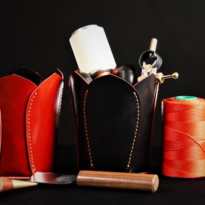 May include: Three red leather tulip-shaped containers, one with a black leather container filled with tools, a spool of red thread, and a wooden tool.