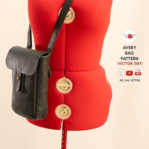 Puede incluir: Un bolso bandolera de cuero negro con cierre de solapa cuelga de un maniquí rojo. El bolso tiene una correa larga y una hebilla. El texto a la derecha dice "AVERY BAG PATTERN VECTOR (DXF)".