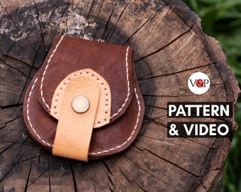 May include: A brown leather coin purse with a beige leather flap and a metal snap closure. The purse is stitched with white thread and has a decorative stitch pattern around the edges. The purse is sitting on a wooden surface.