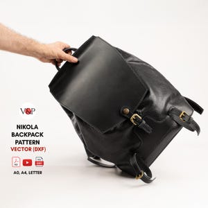 Può includere: Uno zaino in pelle nera con chiusura a patta e fibbie color oro. Lo zaino ha una maniglia superiore e spallacci regolabili. Il testo "NIKOLA BACKPACK PATTERN VECTOR (DXF)" è visibile. Il modello è disponibile nei formati A0, A4 e Letter.