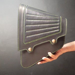 May include: A black leather motorcycle saddlebag with green stitching and metal accents.