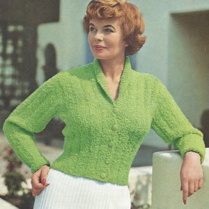 May include: A green knitted cardigan with a collar and buttons. The cardigan is made of poodle wool and is mothproofed. The bust size is 34-36 inches (38-40 inches). The pattern number is 1453 and the price is 6d.