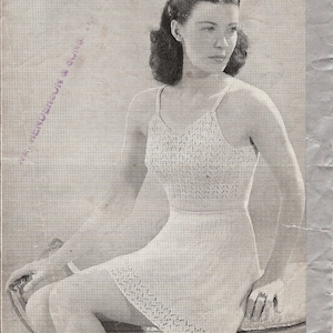 Puede incluir: Una fotografía en blanco y negro de una mujer con un vestido de crochet blanco. El vestido tiene un escote halter y un corpiño ajustado. La mujer está sentada en una silla con las piernas cruzadas. El texto "3D-VEST & KNICKERS-34" BUST-258" está impreso en la parte superior de la imagen. El texto "Patons Halcyon Knitting 2-ply" está impreso en la parte inferior de la imagen.