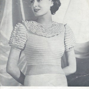 Puede incluir: Una fotografía en blanco y negro de una mujer que lleva un suéter blanco de punto con un cuello y mangas con volantes. El suéter está diseñado para días más cálidos y tiene una circunferencia de pecho de 81-86 cm. El texto "JAEGER" está impreso en negrita en la parte inferior de la imagen. El texto "KNITTING LEAFLET PRICE TWOPENCE" también está impreso en la parte inferior de la imagen. El texto "Number 455 Cost 3/-" está impreso en el centro de la imagen.