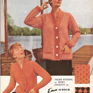 以下が含まれることがあります： ボタン留めのオレンジ色のニットカーディガンを着た女性が2人。左側のカーディガンはドッグトゥース柄、右側のカーディガンは無地。画像には「Emu Scotch Double Knitting」の文字が印刷されています。