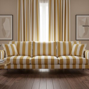 May include: A three-seat sofa upholstered in a mustard yellow and white vertical striped fabric, featuring matching striped cushions, dark wooden legs, and a structured frame, positioned in front of floor-to-ceiling striped curtains.
