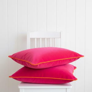 Housse de coussin en velours fuchsia, passepoil orange