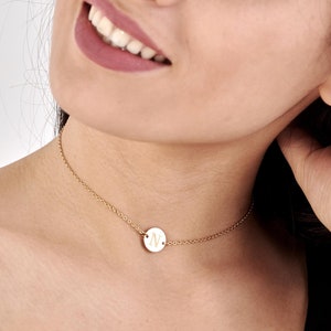 May include: A gold chain necklace with a small round pendant featuring the letter "N" engraved on it.