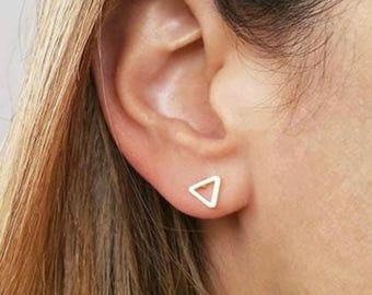 May include: A pair of gold triangle stud earrings. The earrings are simple and minimalist, and they would be a great addition to any jewelry collection.