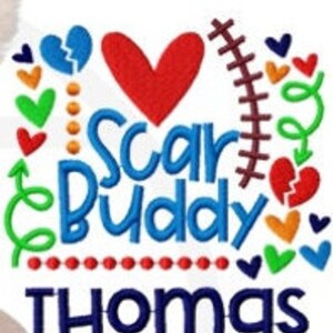 May include: A white background with the words "Scar Buddy" in blue script, and the name "Thomas" in blue block letters. The design includes a red heart, broken hearts, and other colorful heart shapes.