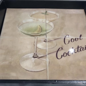 May include: A black serving tray featuring a four-tile insert with a printed graphic of two cocktail glasses and the text Cool Cocktail. The tray has integrated side handles and a smooth, dark frame surrounding the central decorative tile surface.