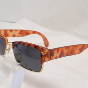 May include: Tortoise shell sunglasses with gold metal accents and dark lenses.