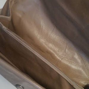 K&ouml;nnte beinhalten: Das Innere einer hellbraunen Ledertasche mit Rei&szlig;verschluss. Die Tasche hat ein glattes Lederfutter.