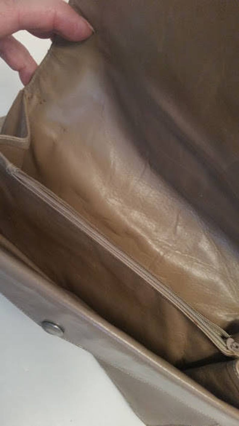 K&ouml;nnte beinhalten: Das Innere einer hellbraunen Ledertasche mit Rei&szlig;verschluss. Die Tasche hat ein glattes Lederfutter.