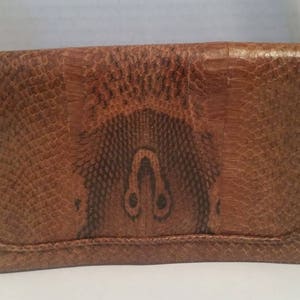 K&ouml;nnte beinhalten: Eine braune Lederschultertasche mit Schlangenhautmuster. Die Tasche hat einen Klappenverschluss und einen einzigen Riemen.