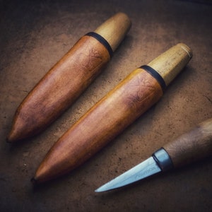 Op de afbeelding: Twee bruine messen met houten handvatten en zwarte accenten en een derde mes met een bruin houten handvat en een zilveren lemmet.