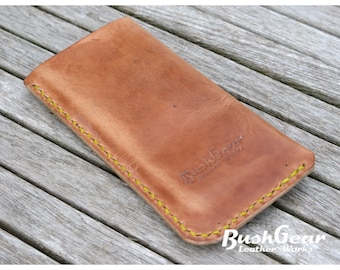 May include: A brown leather phone case with yellow stitching. The case has the text "BushGear Leather Works" embossed on the front.
